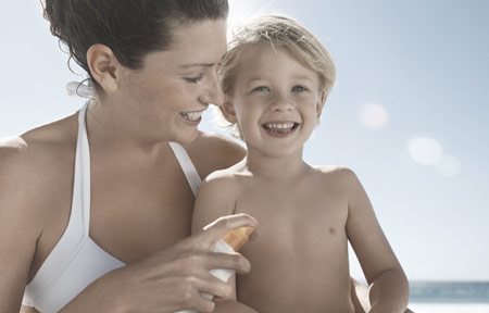 Mutter trägt Sonnenschutzmittel auf