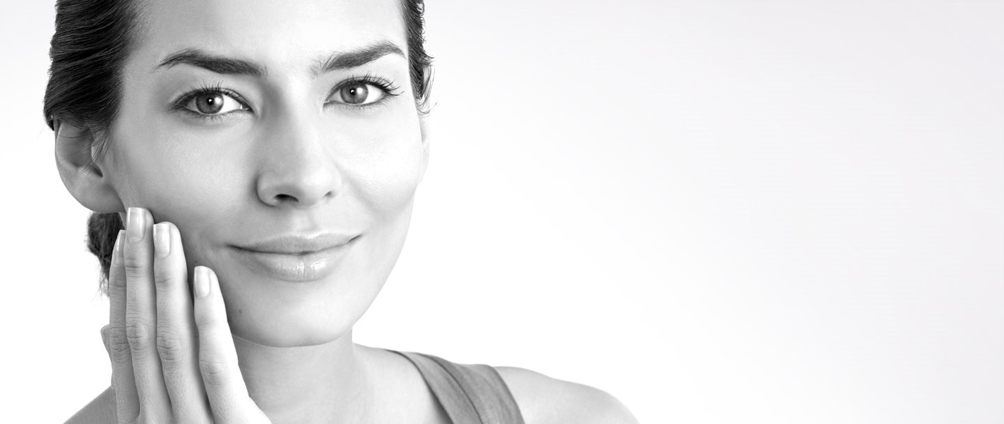 Frau mittleren Alters berührt mit der Hand die rechte Wange.