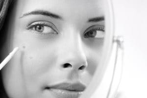 Frau wendet den Korrekturstift gegen Pigmentflecken an.