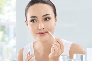 Frau wendet den Korrekturstift gegen Pigmentflecken an.